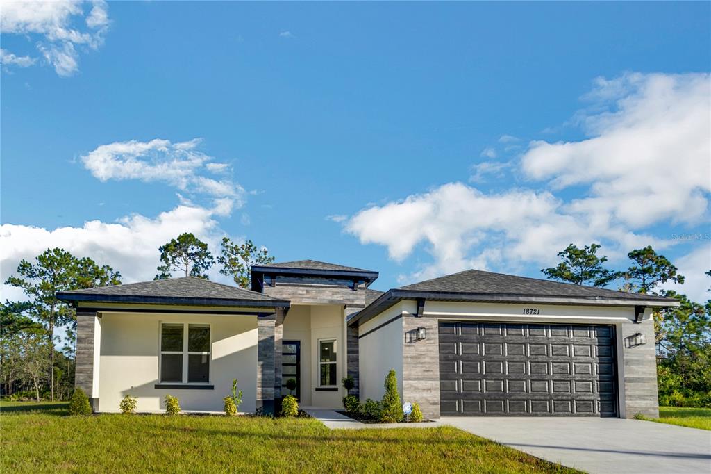 A modern house exterior features a covered porch, stone-accented columns, and a glass-paneled front door — 3724 CORONET AVENUE, ORLANDO, FL