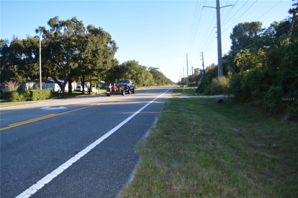 A paved road stretches into the distance with a truck towing a trailer ahead — 0 CHULUOTA ROAD, OVIEDO, FL