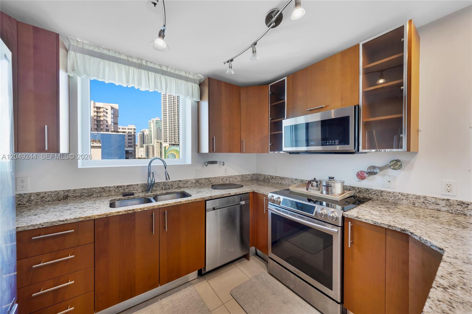 A kitchen features wood cabinets, granite countertops, stainless steel appliances, and a city view window — 1945 S Ocean Dr # 714, Hallandale Beach FL 33009, HALLANDALE BEACH, FL