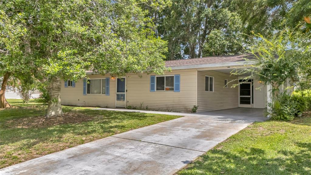 A single-story house with beige siding, blue shutters, and an attached carport — 6446 SW 106TH PLACE, OCALA, FL