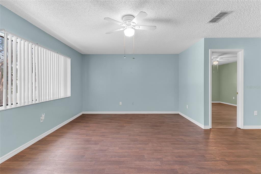 An empty room with light blue walls, wood-look flooring, and a white ceiling fan — 6446 SW 106TH PLACE, OCALA, FL