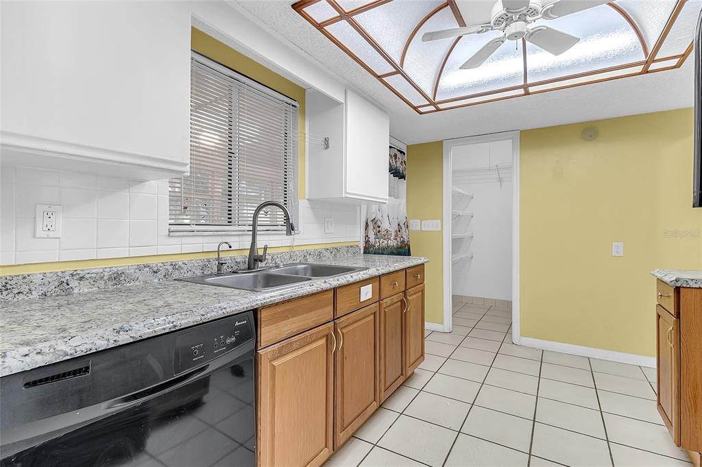 A kitchen with wood cabinets, granite countertops, a double sink, and a walk-in pantry — 6446 SW 106TH PLACE, OCALA, FL