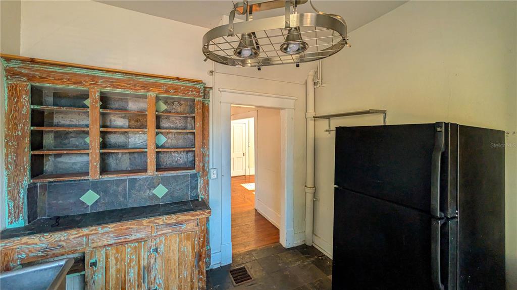 A kitchen features a rustic wooden hutch, a black refrigerator, and a metal light fixture — 610 4TH AVENUE S, ST PETERSBURG, FL