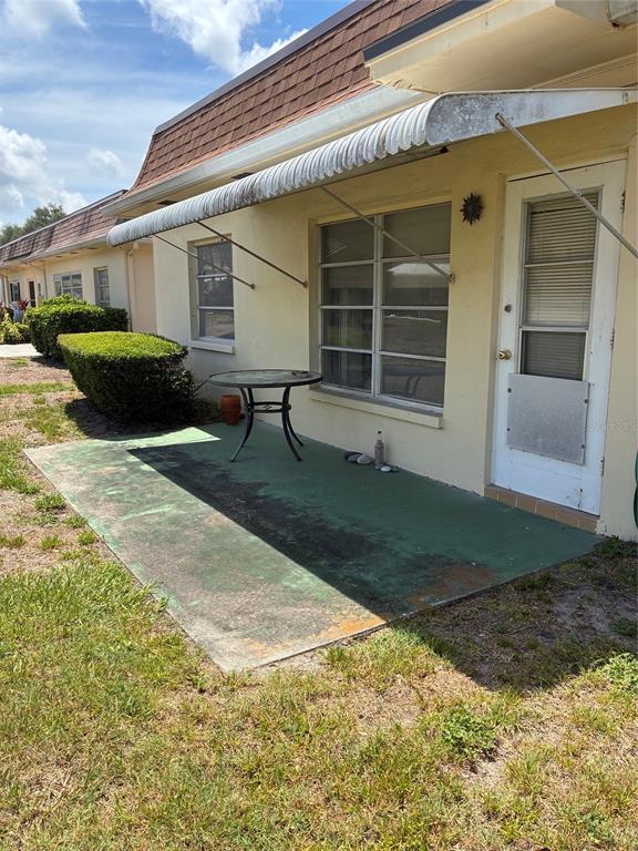 A concrete patio with a small table sits outside a building with a metal awning — 1657 S LAKE AVENUE UNIT 1, CLEARWATER, FL