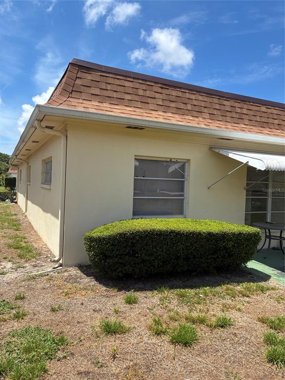 The exterior of a beige house features a brown mansard roof and a large hedge — 1657 S LAKE AVENUE UNIT 1, CLEARWATER, FL