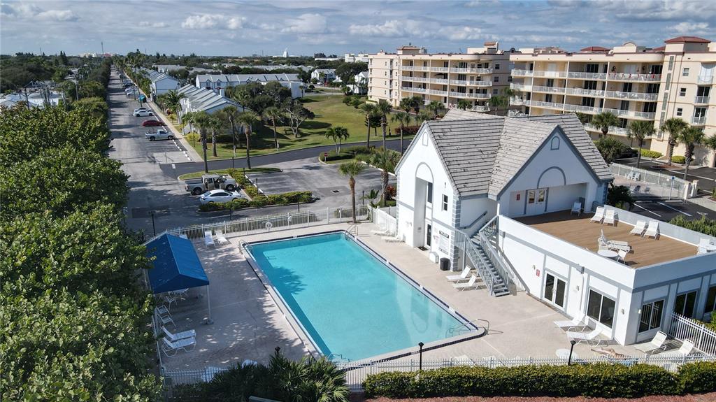An aerial view shows a swimming pool next to a clubhouse with a rooftop deck — 608 BEACH PARK LANE UNIT V257, CAPE CANAVERAL, FL