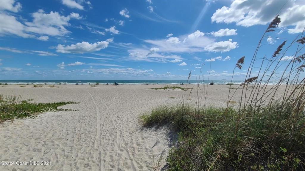 A sandy beach path leads toward the ocean under a blue sky with scattered clouds — 608 BEACH PARK LANE UNIT V257, CAPE CANAVERAL, FL