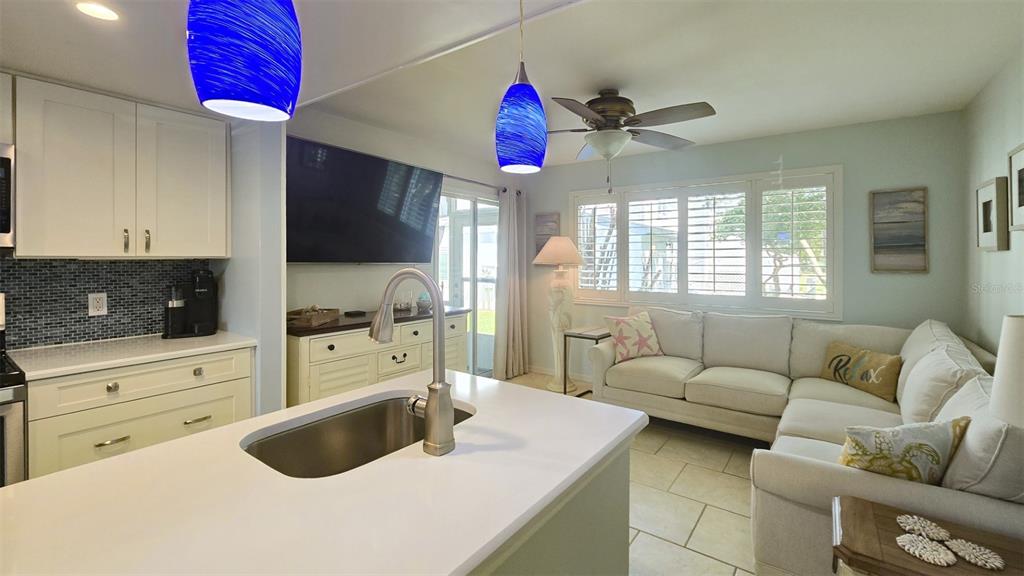 A kitchen island with a sink overlooks a living area featuring a white sectional sofa — 608 BEACH PARK LANE UNIT V257, CAPE CANAVERAL, FL