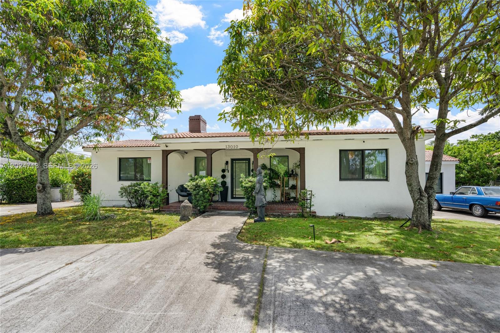 A white single-story house features a covered front porch, a chimney, and mature trees — 13010 Griffing Blvd, North Miami FL 33161, NORTH MIAMI, FL