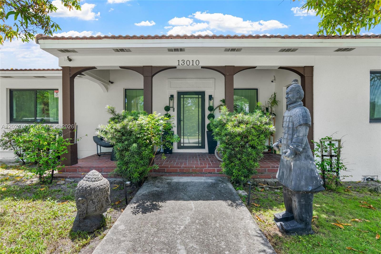 The exterior of a house features a brick porch, a concrete walkway, and two statues — 13010 Griffing Blvd, North Miami FL 33161, NORTH MIAMI, FL