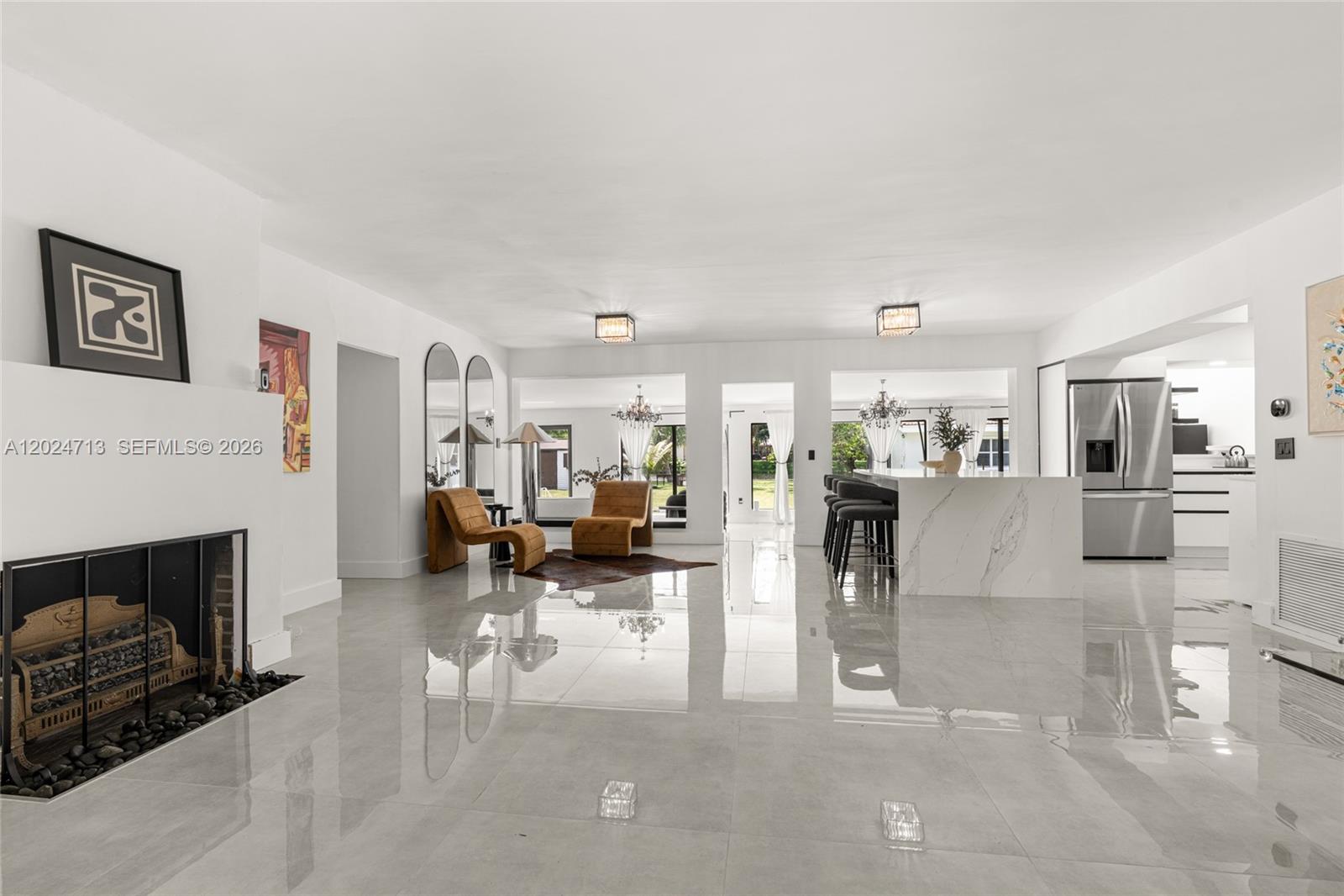 A bright, open-concept living and kitchen area features white walls, glossy tile floors, and a fireplace — 13010 Griffing Blvd, North Miami FL 33161, NORTH MIAMI, FL