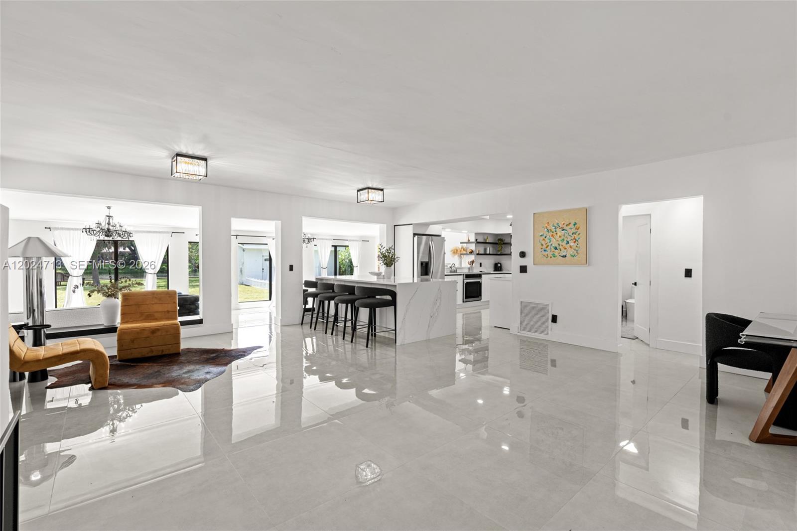 A bright, open-concept living and kitchen area features white walls, glossy tile floors, and a marble island — 13010 Griffing Blvd, North Miami FL 33161, NORTH MIAMI, FL