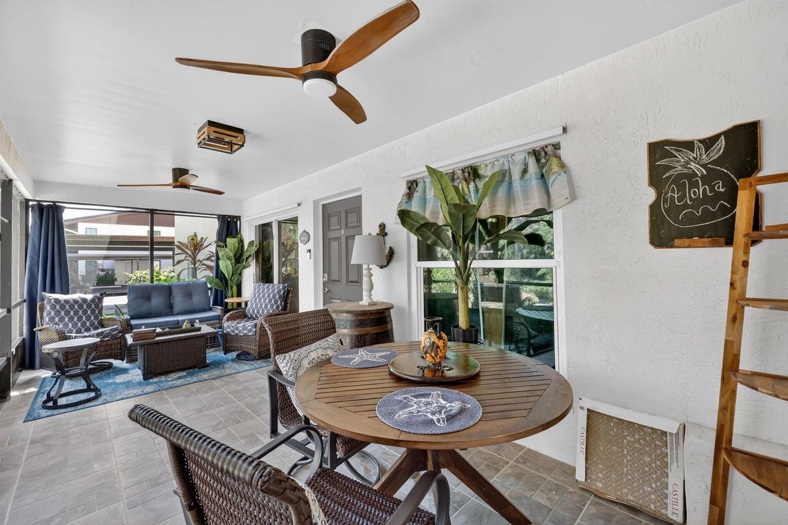 A covered patio features a dining set, wicker seating, ceiling fans, and a tiled floor — 6531 SE Federal Highway # 103, Stuart FL 34997, STUART, FL