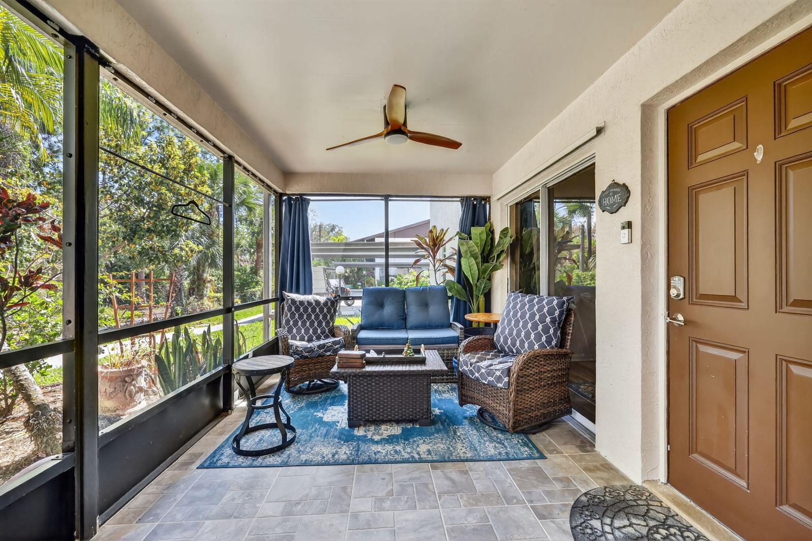 A screened-in patio features tiled flooring, wicker furniture with blue cushions, and a ceiling fan — 6531 SE Federal Highway # 103, Stuart FL 34997, STUART, FL