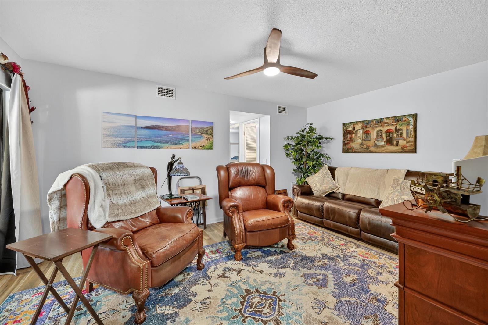 A living room features leather seating, a patterned area rug, and a ceiling fan — 6531 SE Federal Highway # 103, Stuart FL 34997, STUART, FL