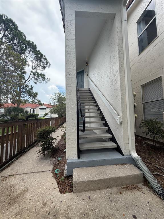 An exterior view of a concrete staircase leading to an upper-level apartment entrance — 5168 CONROY ROAD UNIT 28, ORLANDO, FL