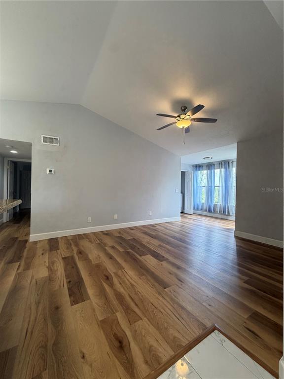 A living room features vaulted ceilings, wood-look flooring, and a ceiling fan — 5168 CONROY ROAD UNIT 28, ORLANDO, FL