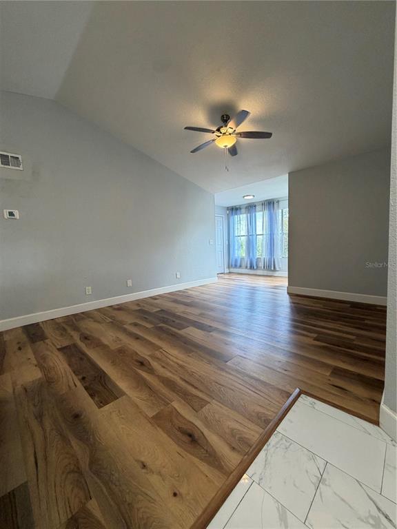 A living room features wood-look flooring, a vaulted ceiling with a fan, and light-colored walls — 5168 CONROY ROAD UNIT 28, ORLANDO, FL