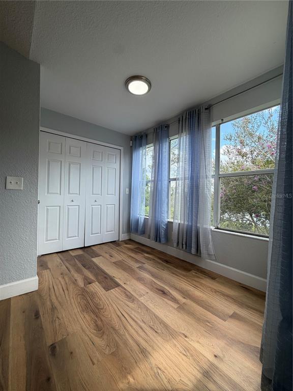 A small room features wood-look flooring, white bi-fold closet doors, and windows with blue curtains — 5168 CONROY ROAD UNIT 28, ORLANDO, FL