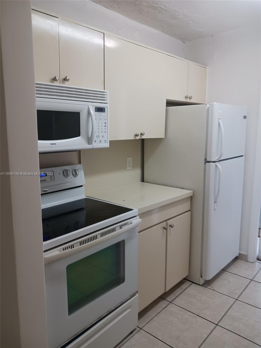 A kitchen features white appliances, light-colored cabinets, and tile flooring — 2700 NE 135th St # 30, North Miami FL 33181, NORTH MIAMI, FL