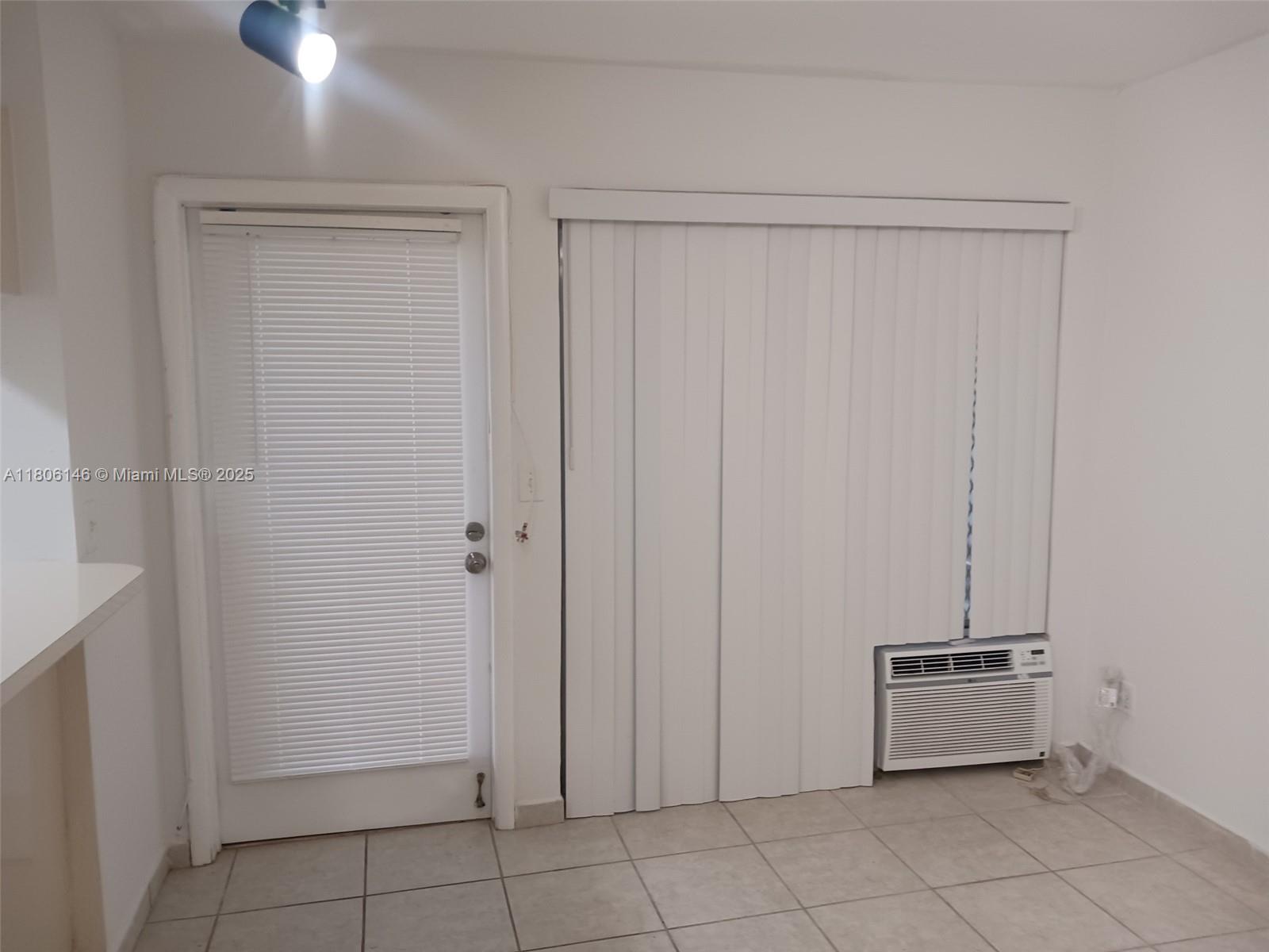 A room features a white door with blinds, vertical blinds over a window, and an air conditioner — 2700 NE 135th St # 30, North Miami FL 33181, NORTH MIAMI, FL