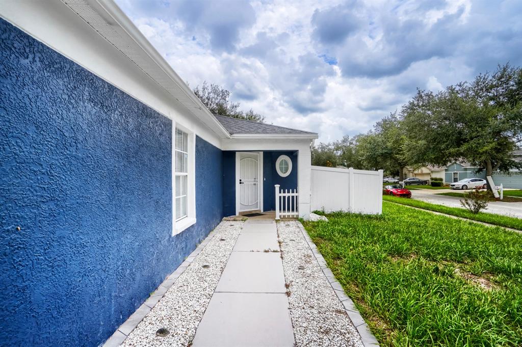 A blue stucco house exterior features a white front door, walkway, and white privacy fence — 701 PERIWINKLE POINTE PLACE, SEFFNER, FL