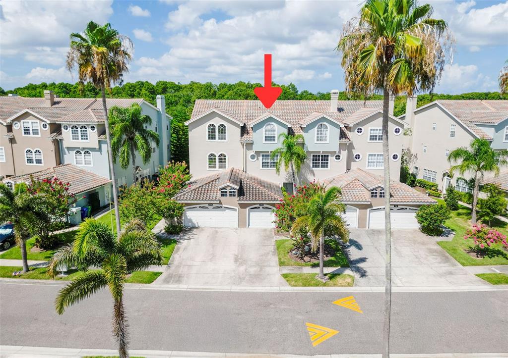 An aerial view shows a multi-story townhouse complex with a red arrow pointing to a unit — 1722 ARABIAN LANE, PALM HARBOR, FL