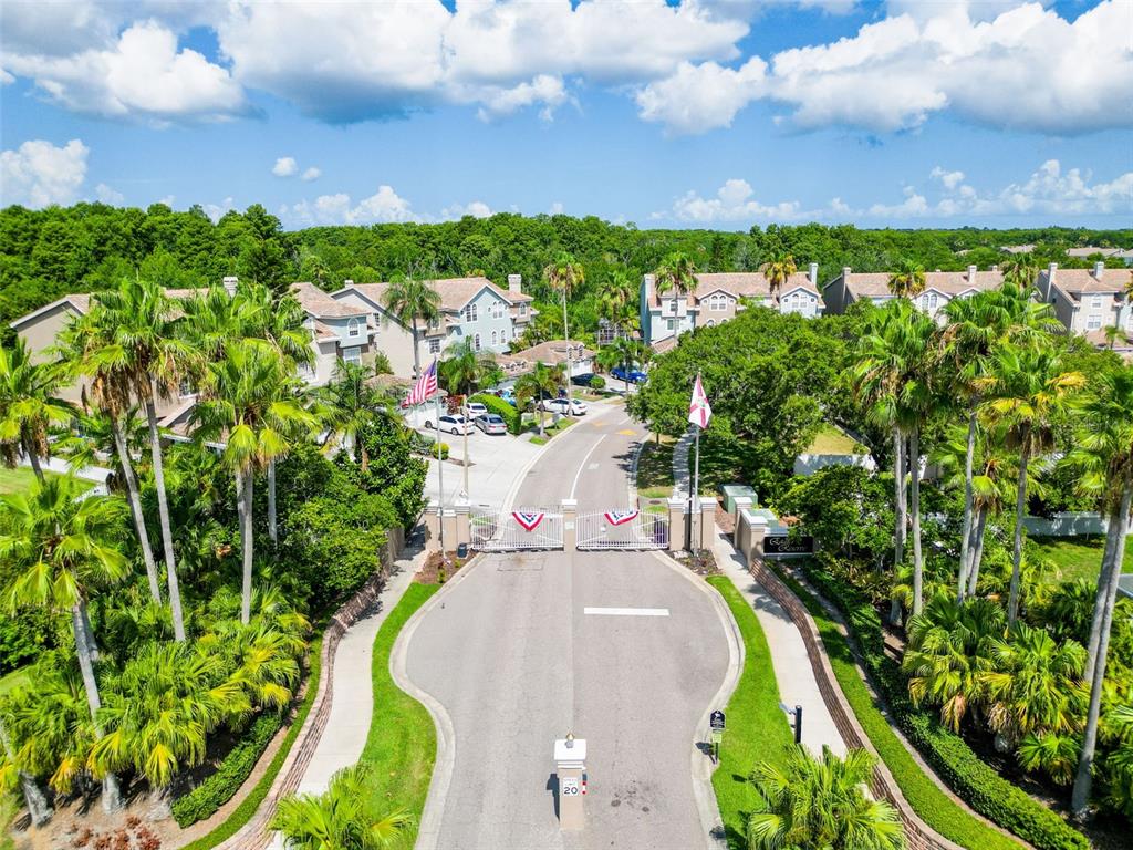 An aerial view shows a gated entrance to a residential community with palm trees — 1722 ARABIAN LANE, PALM HARBOR, FL