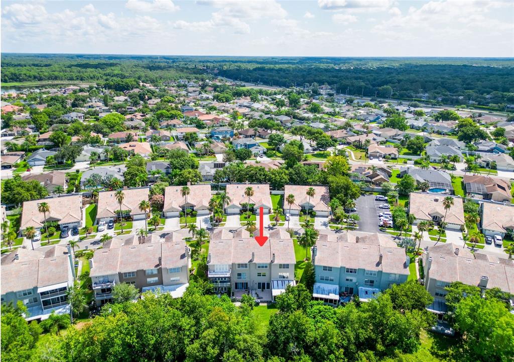 An aerial view shows a multi-story residential townhouse complex surrounded by trees and suburban homes — 1722 ARABIAN LANE, PALM HARBOR, FL
