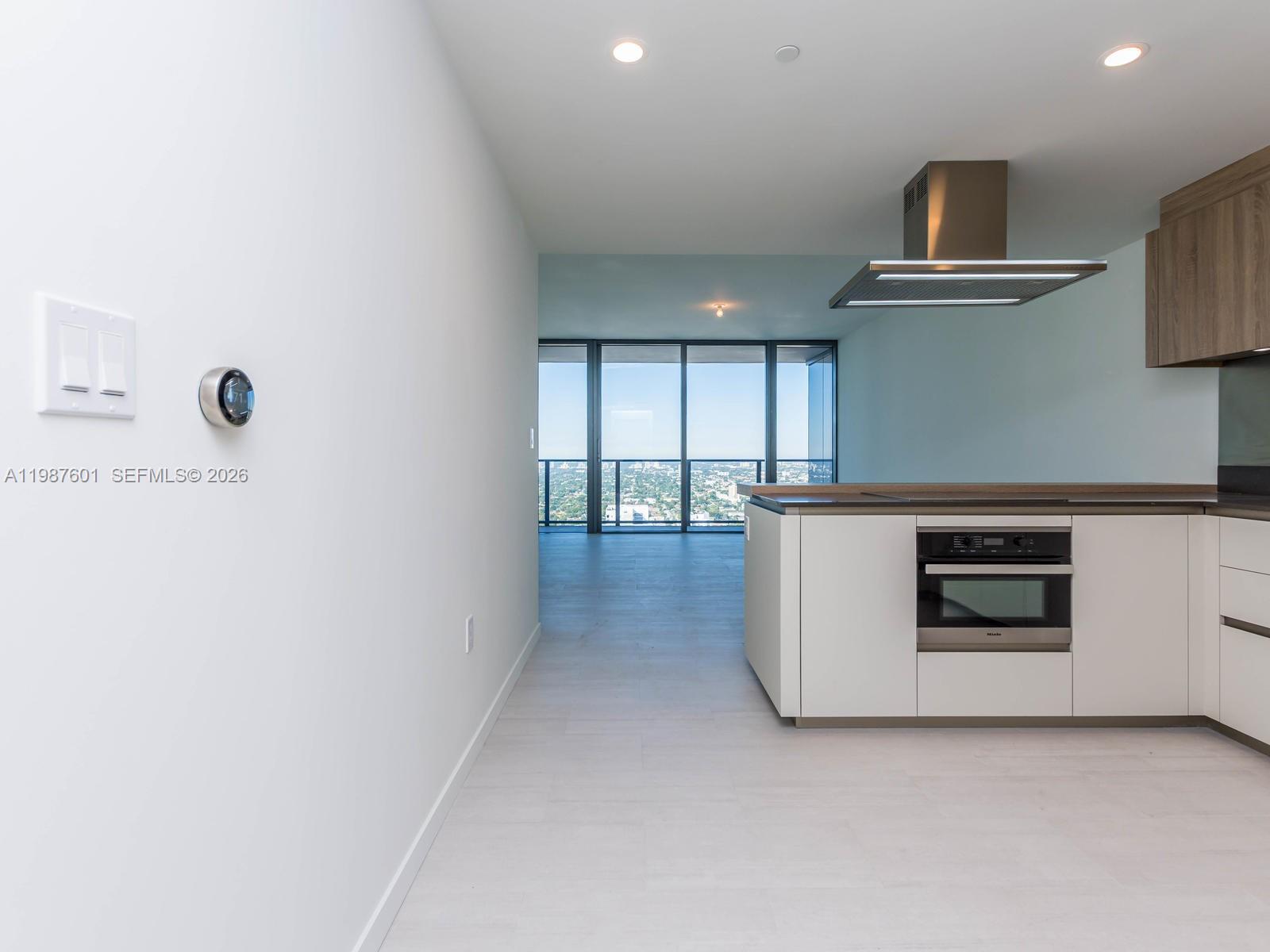 A modern kitchen features white cabinetry, a built-in oven, and a view of the city — 1000 Brickell Plz # 4104, Miami FL 33131, MIAMI, FL
