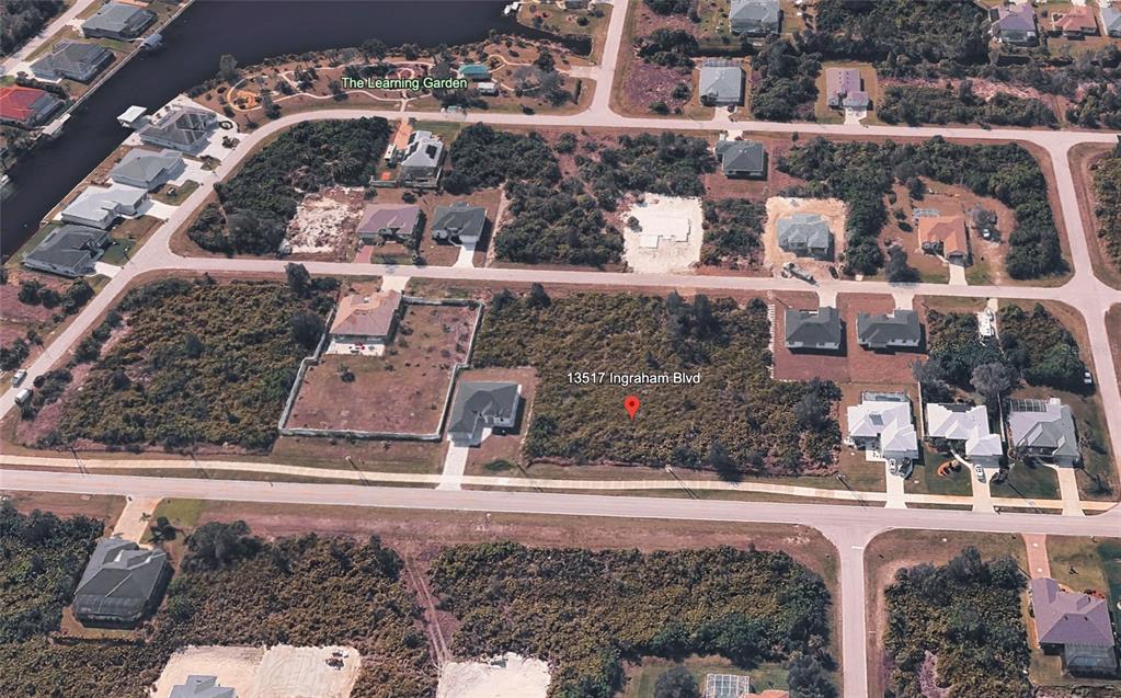 This aerial view shows a vacant residential lot surrounded by houses and wooded areas — 13509 & 13517 INGRAHAM BOULEVARD, PORT CHARLOTTE, FL