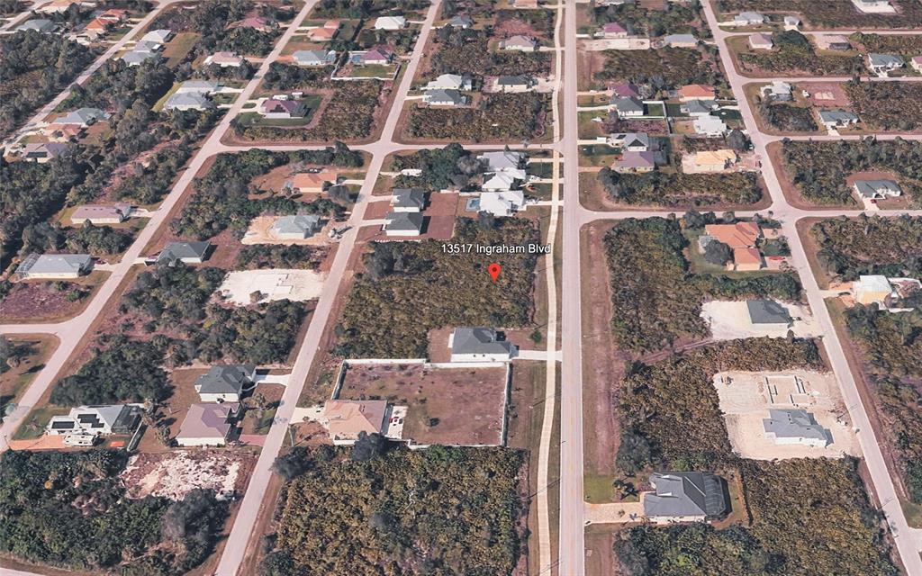 This aerial view shows a vacant residential lot surrounded by houses and undeveloped land — 13509 & 13517 INGRAHAM BOULEVARD, PORT CHARLOTTE, FL