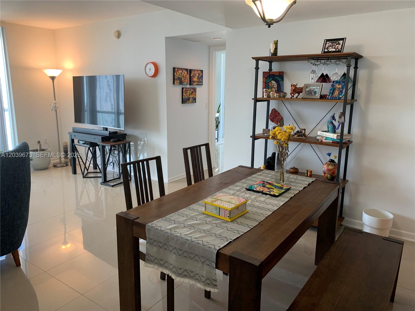 A dining area with a wooden table and shelving unit sits adjacent to a living room — 50 Biscayne Blvd # 3001, Miami FL 33132, MIAMI, FL