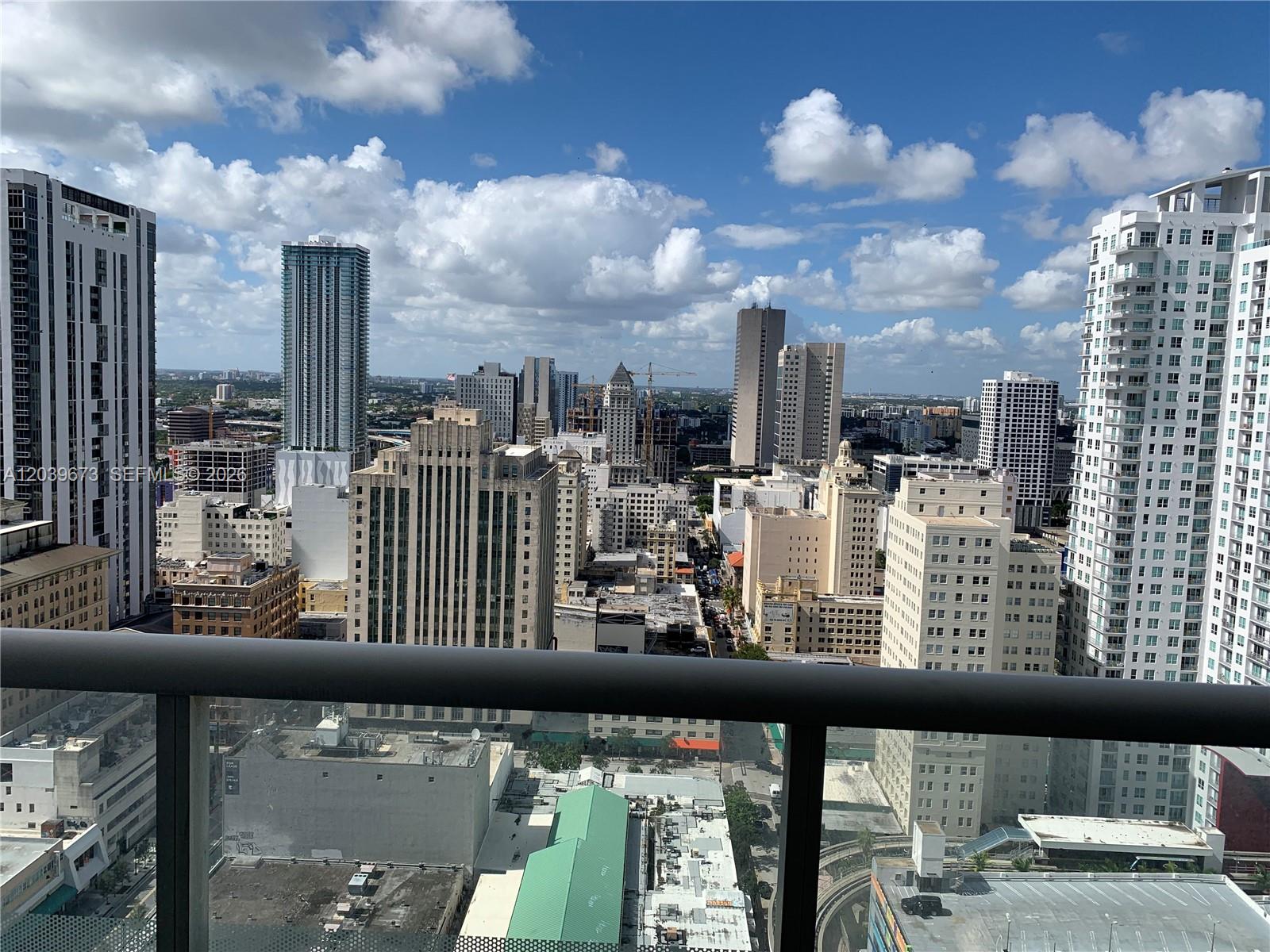 A high-angle view of a city skyline featuring various skyscrapers under a cloudy blue sky — 50 Biscayne Blvd # 3001, Miami FL 33132, MIAMI, FL