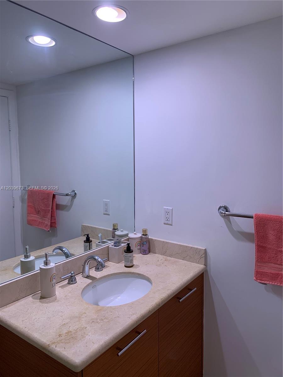 A bathroom features a wood vanity with a stone countertop, a large mirror, and pink towels — 50 Biscayne Blvd # 3001, Miami FL 33132, MIAMI, FL
