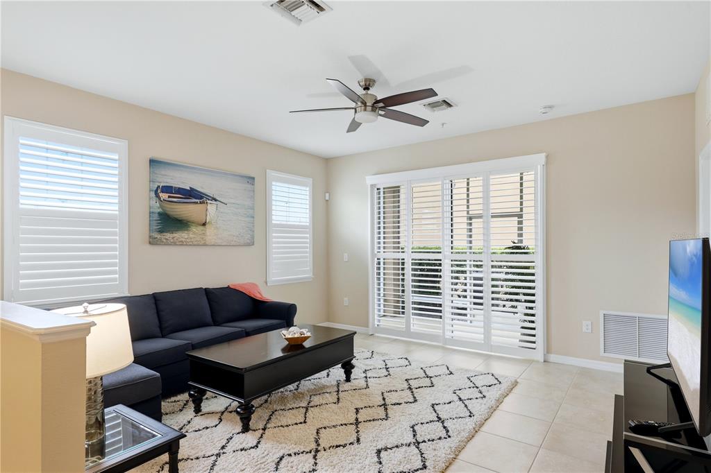 A living room features a dark sofa, a coffee table, a rug, and sliding glass doors — 8423 KARPEAL DRIVE UNIT 1501, SARASOTA, FL