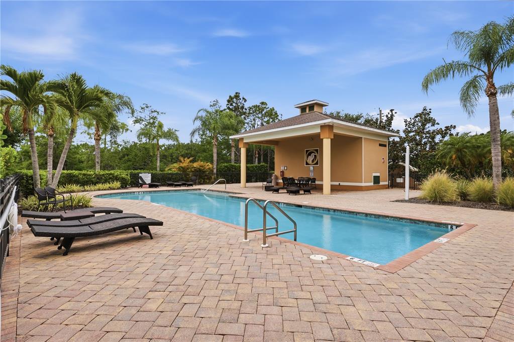 A rectangular swimming pool with a covered pavilion and lounge chairs on a brick patio — 8423 KARPEAL DRIVE UNIT 1501, SARASOTA, FL