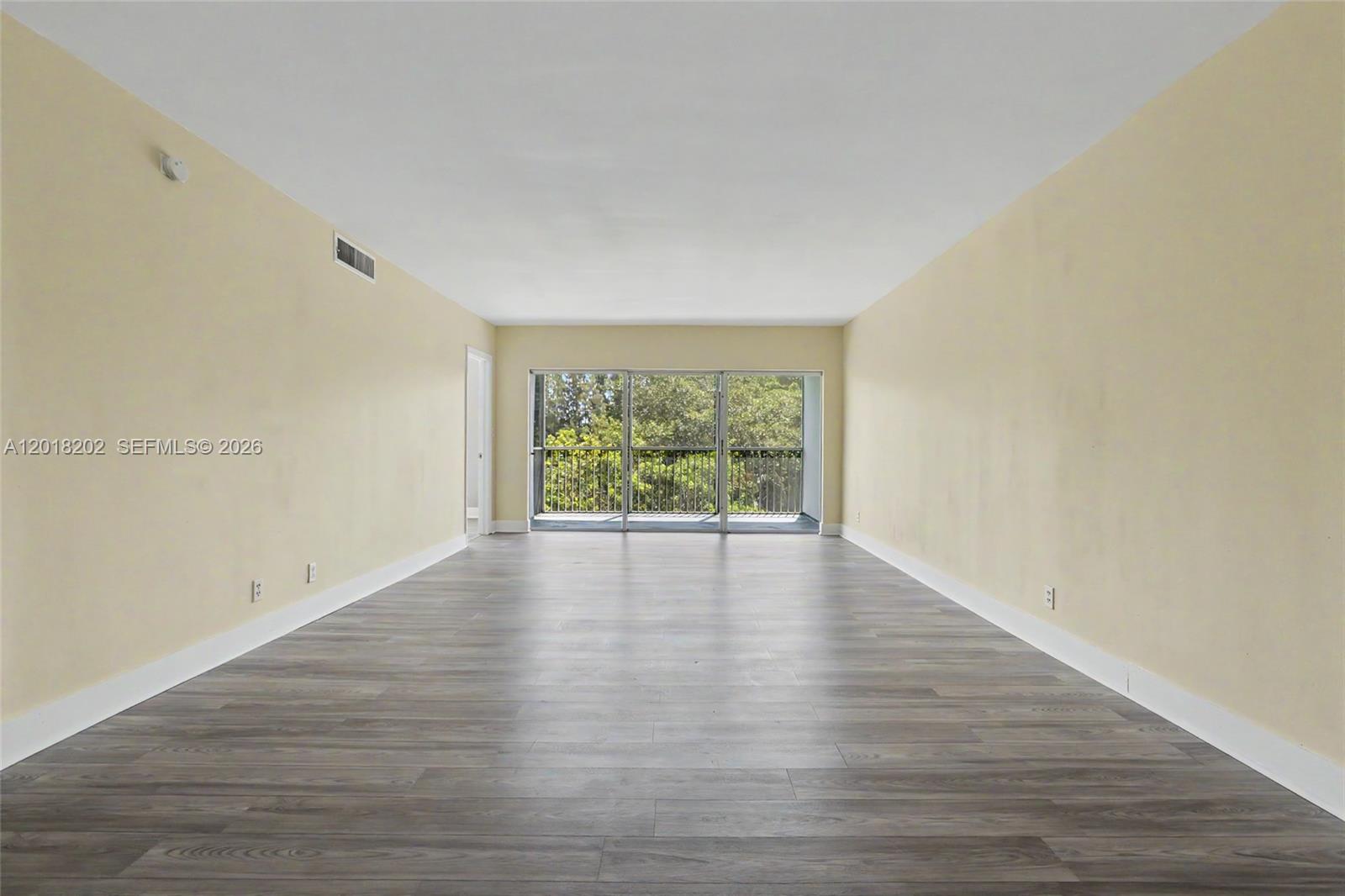This living room features light wood flooring, a beige sofa, and a balcony with greenery — 3250 N Palm Aire Dr # 406, Pompano Beach FL 33069, POMPANO BEACH, FL