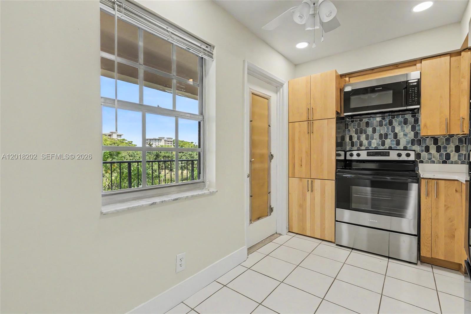 An empty room features light-colored walls, wood-look flooring, and a sliding glass door to a balcony — 3250 N Palm Aire Dr # 406, Pompano Beach FL 33069, POMPANO BEACH, FL