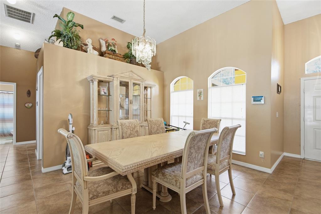 A dining room features a light wood table, matching chairs, a hutch, and arched windows — 9602 SUNNYOAK DRIVE, RIVERVIEW, FL