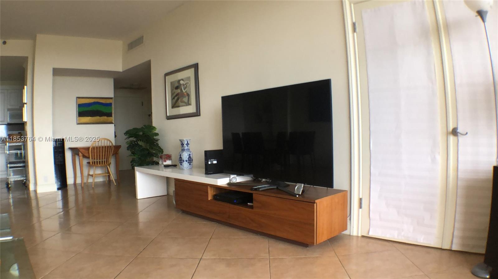 A living room features a large television on a wooden console, tile flooring, and artwork — 151 Crandon Blvd # 833, Key Biscayne FL 33149, KEY BISCAYNE, FL