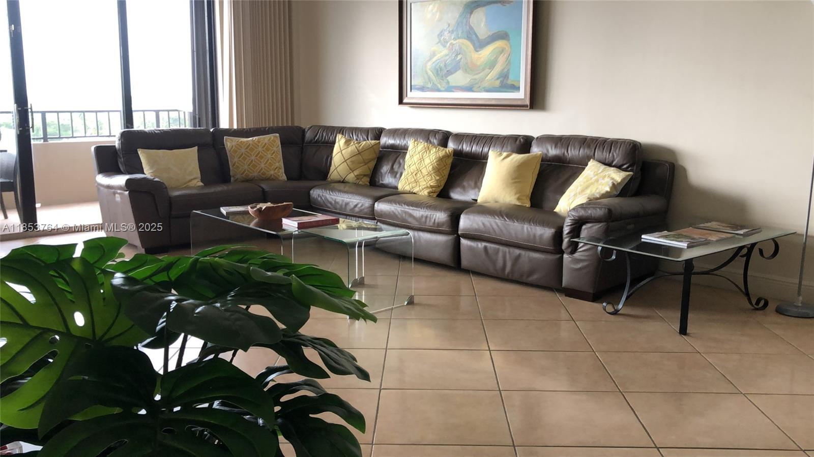 A living room features a large brown leather sectional, glass coffee tables, and tile flooring — 151 Crandon Blvd # 833, Key Biscayne FL 33149, KEY BISCAYNE, FL