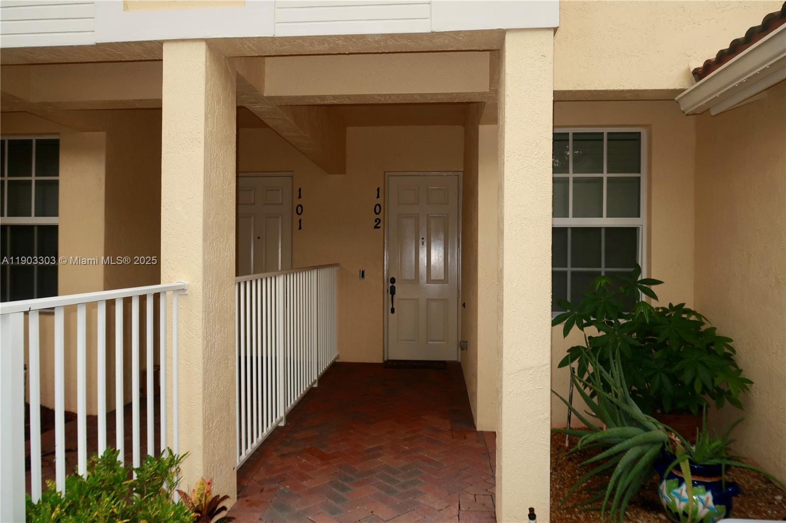The exterior entrance features a brick walkway leading to two adjacent doors numbered 101 and 102 — 9778 Bowline Drive # 102, West Palm Beach FL 33411, WEST PALM BEACH, FL