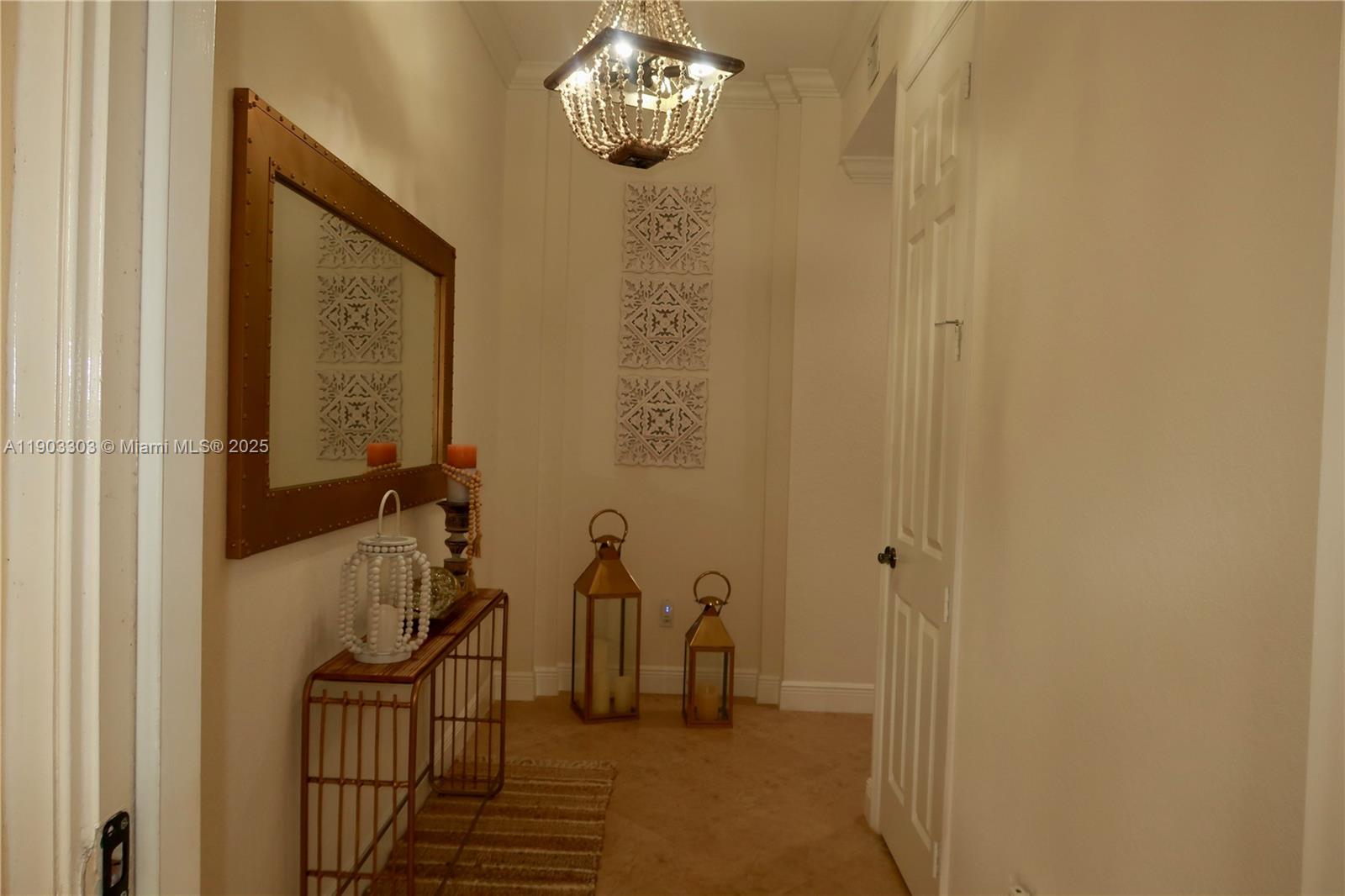 A hallway features a console table, a large mirror, decorative wall panels, and lantern decor — 9778 Bowline Drive # 102, West Palm Beach FL 33411, WEST PALM BEACH, FL