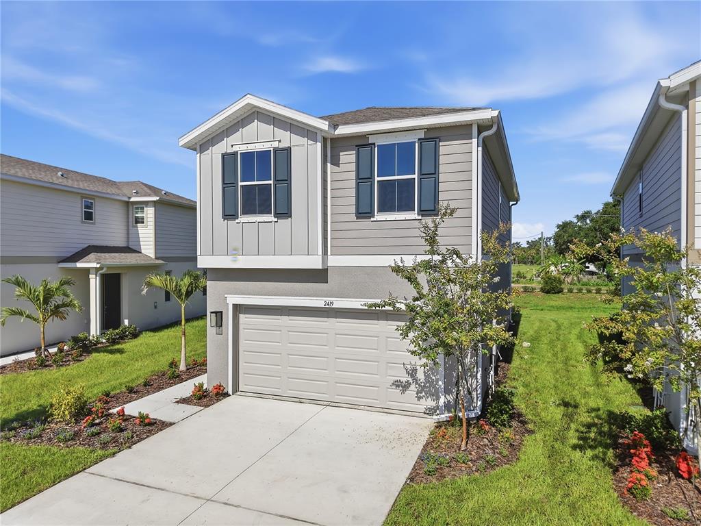 A two-story house with a beige garage, gray siding, and a concrete driveway — 2419 29TH LANE E, PALMETTO, FL
