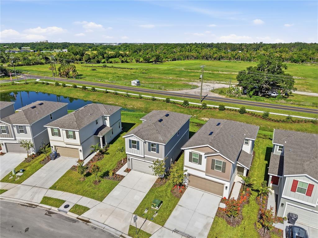 An aerial view shows a row of suburban houses with driveways facing a road and field — 2419 29TH LANE E, PALMETTO, FL