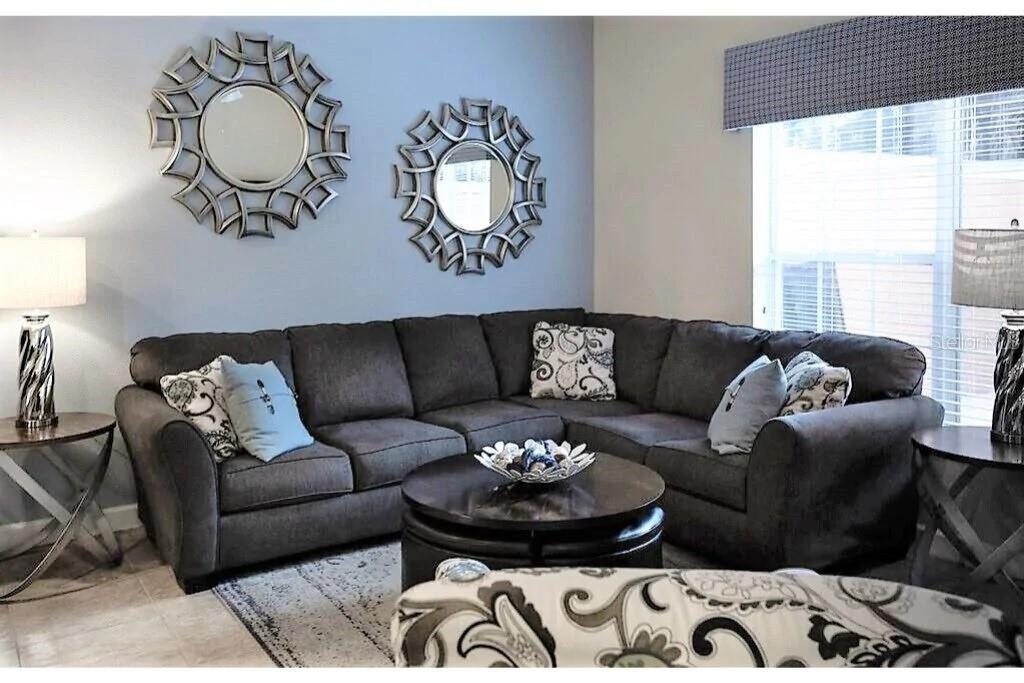 A living room features a dark gray sectional sofa, two round mirrors, and side tables — 2945 BANANA PALM DRIVE, KISSIMMEE, FL