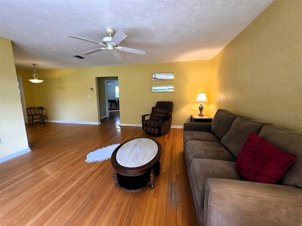 A living room features hardwood floors, a ceiling fan, a sofa, and a recliner — 735 OVERHILL ROAD, DELAND, FL