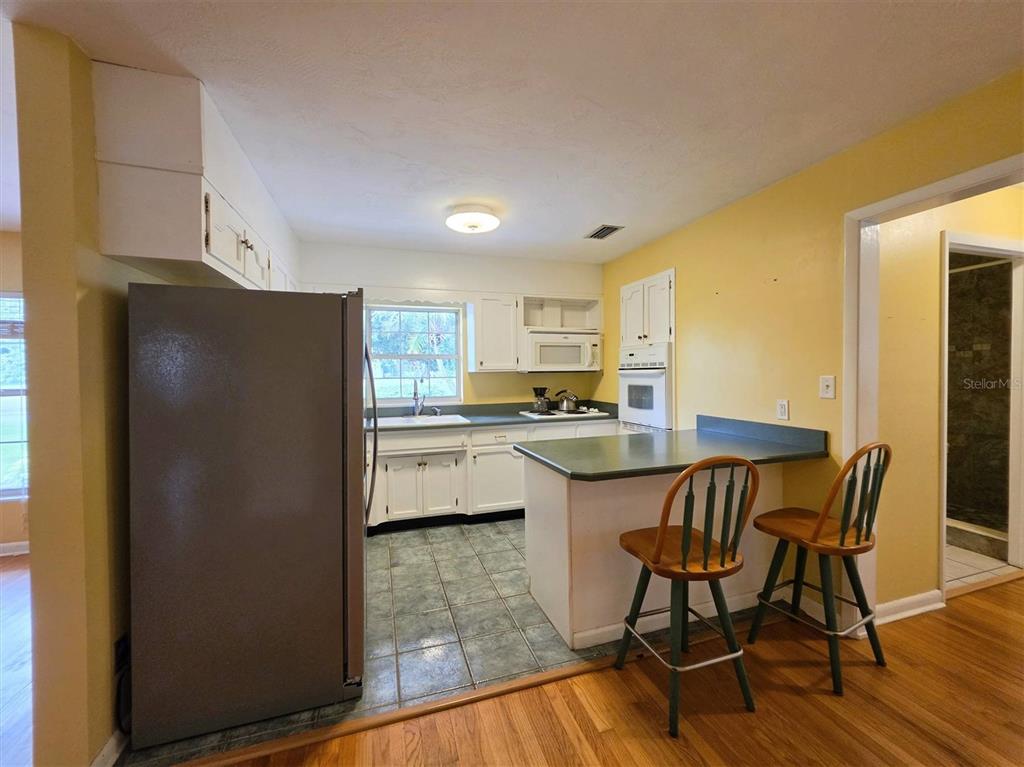 A kitchen features white cabinets, a green countertop, a breakfast bar, and tile flooring — 735 OVERHILL ROAD, DELAND, FL