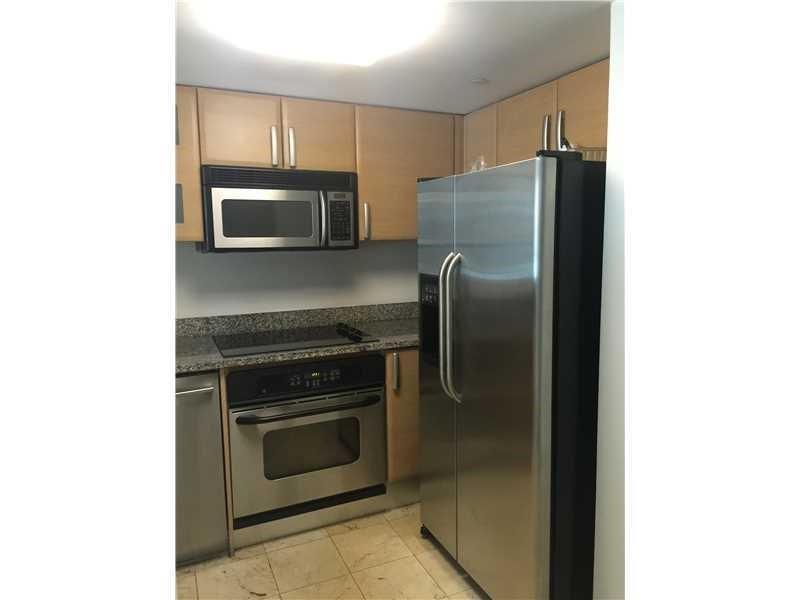 A kitchen features light wood cabinets, stainless steel appliances, and granite countertops — 2101 Brickell Avenue # 808, Miami FL 33129, MIAMI, FL